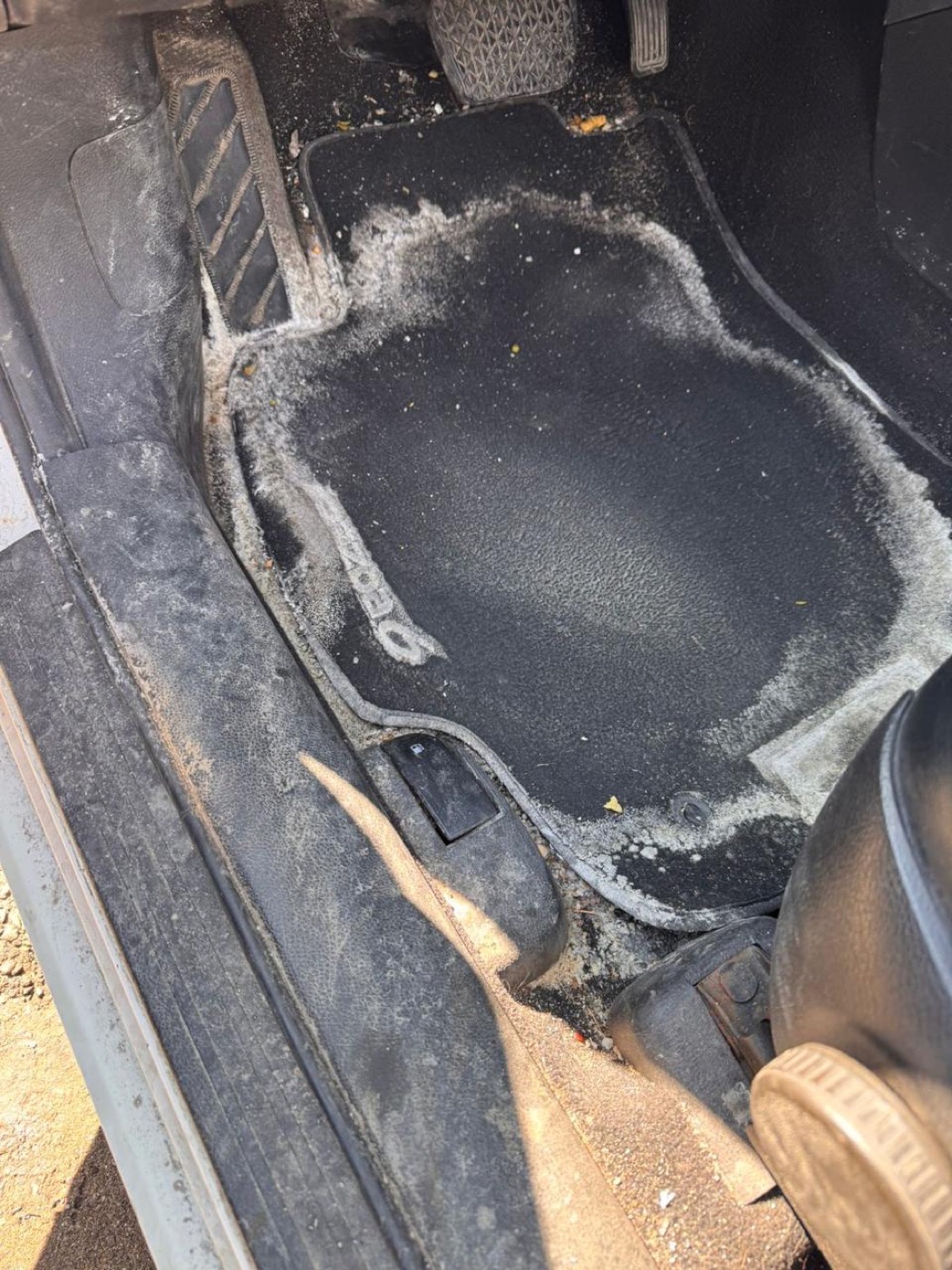 Car floor mat covered in white winter salt stains before, and clean footwell after salt removal โ before